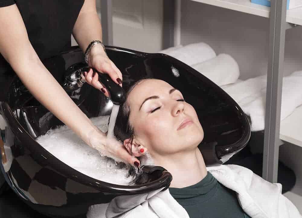 hairdresser washes woman hair